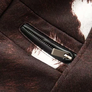 Detail of dark brown vintage jacket with white cow print and faux leather zipper pocket