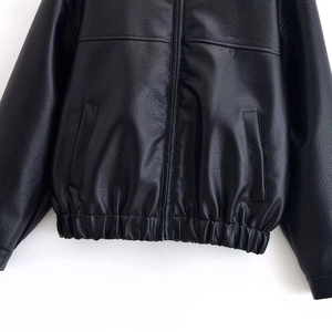 Détail de la veste en cuir noir avec texture grainée, fermeture éclair et taille élastique