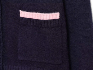Detail view of navy blue knit sweater featuring a contrasting pink ribbed pocket edge