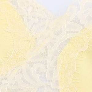 Close-up of pale yellow floral lace fabric with delicate eyelash trim detailing