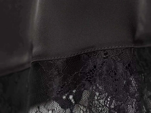 Macro shot of elegant black satin fabric featuring intricate floral lace stitching details