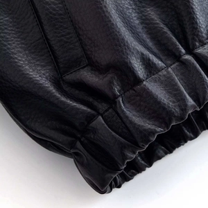Gros plan du poignet élastique d'une veste en cuir noir avec texture grainée de qualité
