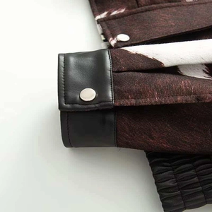 Close-up of jacket cuff with black leather contrast, silver snap button and ribbed trim