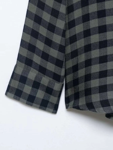 Detail view of the gingham plaid pattern and cuff stitching on this loose gray shirt