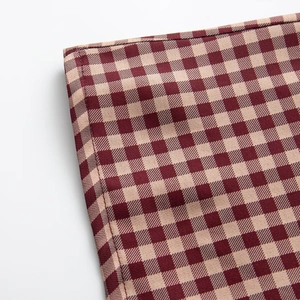 Detail of burgundy and beige gingham fabric showing precise double-needle stitching quality