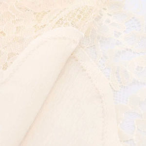 Détails de la dentelle beige délicate avec motif floral sur la robe asymétrique