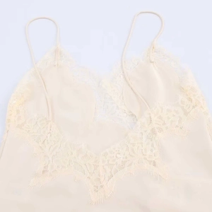 Détail de la dentelle sur le décolleté en V d'un caraco beige en tissu soyeux