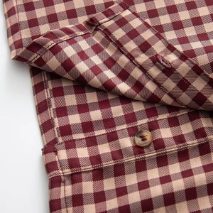 Detail shot of wine red gingham fabric with a premium amber button on the shirt