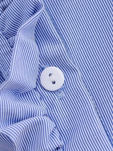 Close-up of blue and white striped shirt fabric with a white round button and woven texture