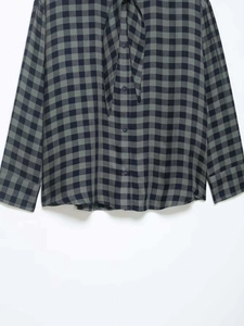 Detail of navy blue gingham shirt featuring a tie-neck collar and button-down front