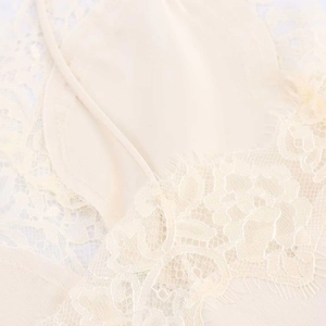 Détail d'une robe en dentelle beige avec motifs floraux et bordure en dentelle délicate