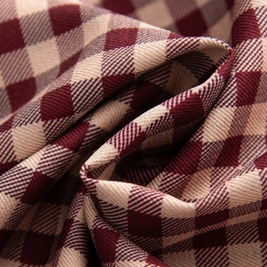 Macro shot of burgundy and beige checkered woven fabric showing soft draped texture