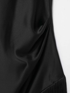 Detail view of smooth black satin top featuring side ruching and elegant tassel fringe hem
