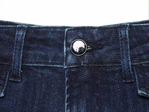 Dettaglio vita jeans blu scuro con passanti per cintura e bottone in metallo nero