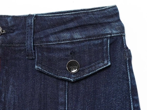 Vista macro del denim blu scuro con cuciture a contrasto, tasca con patta e bottone