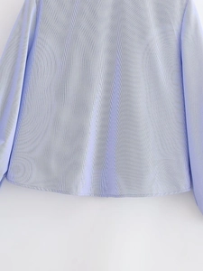 Detail view of blue and white striped shirt with ruffle trim and curved hem fabric