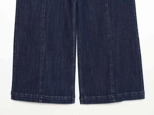 Dettaglio dei jeans larghi blu scuro con cuciture verticali e orlo risvoltato rifinito