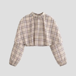 Detail of cropped plaid top featuring cape-style layering and checkered pattern