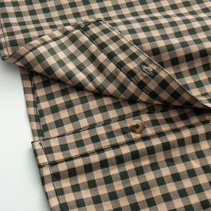 Detailed close-up of brown gingham pattern fabric with polished resin buttons and stitching