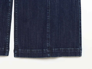 Dettaglio macro dell'orlo dei jeans blu scuro con cuciture e trama in twill di alta qualità