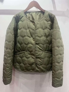 Detailed view of army green quilted jacket with unique hexagonal patterns and snap buttons