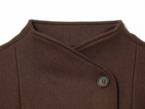 Dettaglio del colletto di un cappotto in lana marrone scuro con chiusura a bottoni