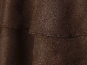 Détail de la jupe marron foncé en simili daim avec couches plissées et coutures fines