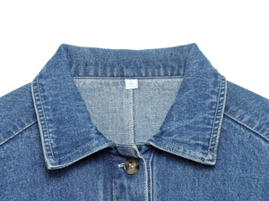 Detailaufnahme eines Jeanshemdkragens mit Harzknopf und Größenetikett S auf weißem Grund