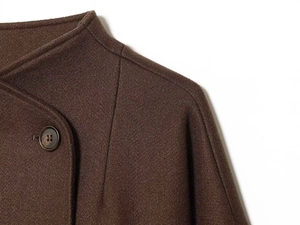 Dettaglio del colletto del cappotto di lana marrone scuro con un grande bottone strutturato