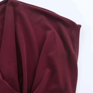 Detail of burgundy cowl neck dress with elegant draped fabric and textured knit material