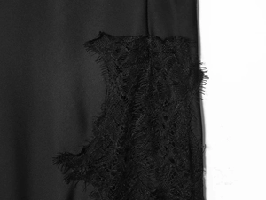 Detail of elegant black satin fabric with intricate eyelash lace trim and refined finish