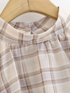 Detail of high collar and back button on plaid sleeveless top in light brown and lavender