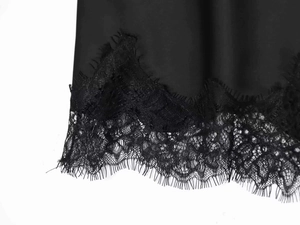 Close-up of black satin skirt hem with elegant eyelash lace and floral embroidery details