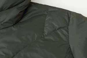 Macro detail of diamond quilted dark olive down jacket with satin finish and fine stitching