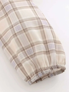 Detail of the elastic cuff and plaid pattern in beige, tan and light purple fabric