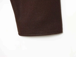 Dettaglio del tessuto in lana color caffè scuro con trama spessa e cuciture precise