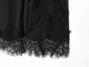 Close-up detail of smooth black satin fabric with delicate eyelash lace hem decoration