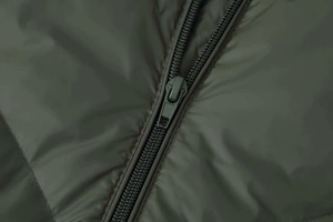 Detail of high-quality zipper on dark olive green puffer jacket with synthetic fabric