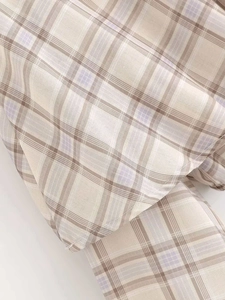 Detailed macro view of beige plaid fabric texture with precise stitching for summer top