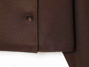Dettaglio di un cappotto di lana marrone scuro con cuciture e bottone strutturato