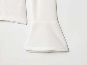 Dettaglio del top bianco che mostra le cuciture di qualità e il design della manica a campana