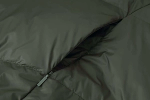 Detail of army green quilted down jacket showing zipper pocket and durable fabric texture