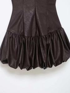 Détail de la robe en similicuir marron foncé avec texture volantée et fini mat