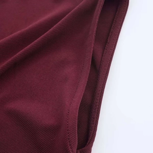 Detailed close-up of dark red ribbed knit fabric with precise stitching and fine texture