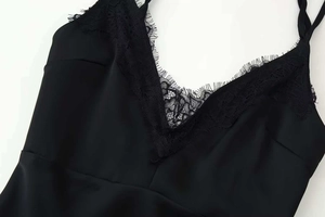 Dettaglio dell'abito in raso nero con scollo a V profondo e rifiniture in pizzo ciglia