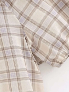 Close-up of plaid fabric short top featuring elastic smocked cuffs and puffy sleeve detail