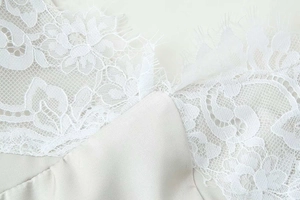 Détail de la dentelle blanche et du satin soyeux sur une robe d'été à bretelles