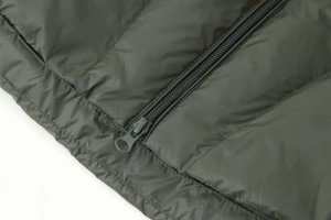 Close-up of olive green quilted down jacket featuring a premium nylon zipper and satin finish