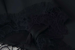 Dettaglio di elegante tessuto in raso nero con bordo in pizzo cigliato per abito lusso