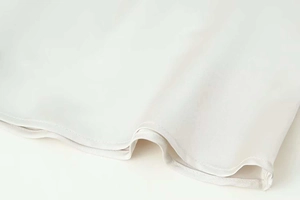 Gros plan du tissu satiné blanc montrant l'ourlet soigné et la texture soyeuse
